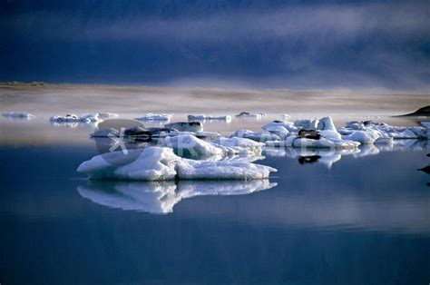 Floating Icebergs Reflected In The Quiet Waters Of Jokulsarlon