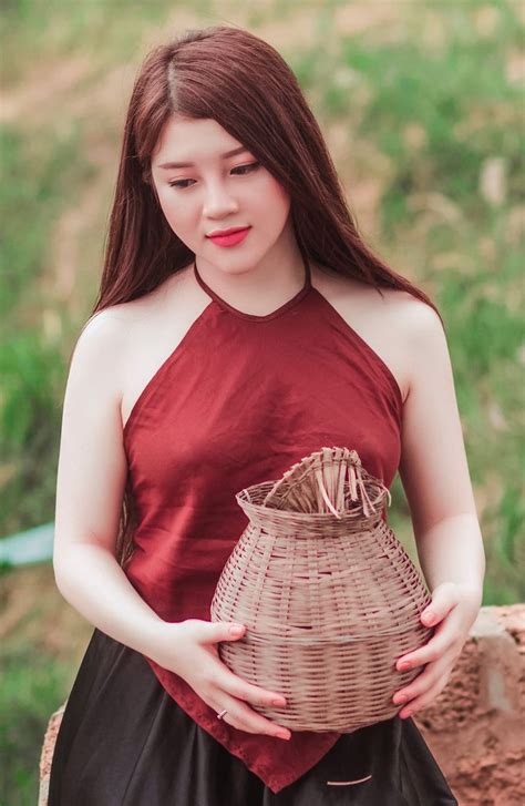 A Woman In A Red Top Is Holding A Woven Basket And Posing For The Camera