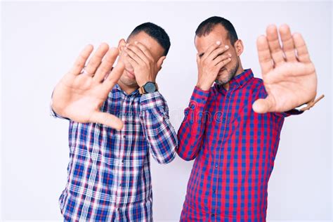 Young Gay Couple Of Two Men Wearing Casual Clothes Covering Eyes With Hands And Doing Stop