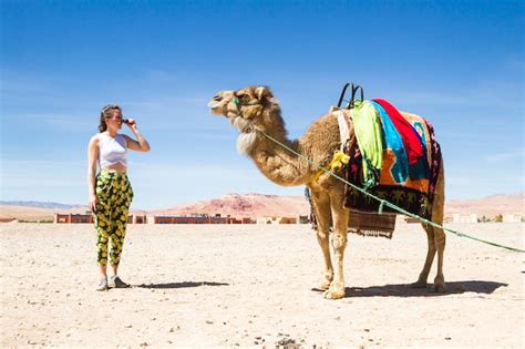 Mujer Joven Que Mira Un Camello En El Desierto Foto Premium