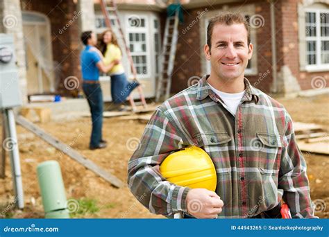 Construction Contractor With Excited Home Owners In Background Stock