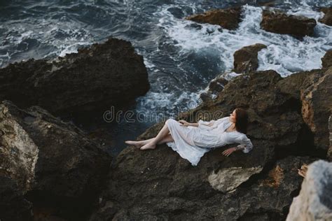Woman Lying On Rocky Coast With Cracks On Rocky Surface View From Above