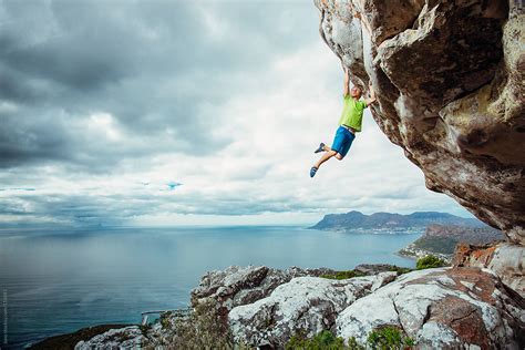 Young Man Rock Climbing On An Overhanging Cliff By Stocksy