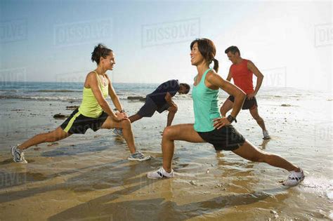 Multi Ethnic Runners Stretching At Beach Stock Photo Dissolve