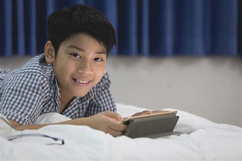 Asian Boy Lying And Playing Game On Digital Tablet At Home Stock Image