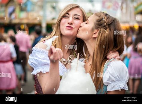 zwei junge frauen in dirndl oder tracht küssen mit baumwolle zuckerwatte auf dem oktoberfest