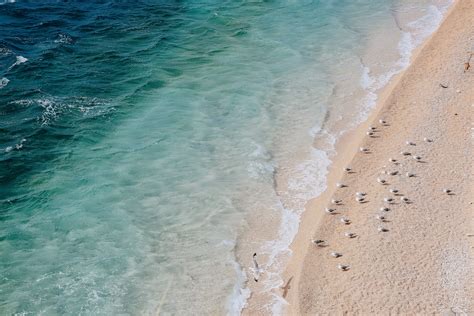 Beautiful Sandy Beach With Waving Ocean On Sunny Day · Free Stock Photo