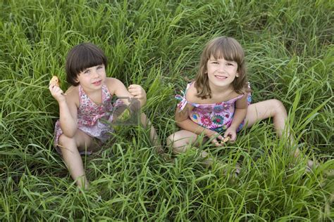 Two Girls Sitting In The Grass In Meadow Summer Time Friendshi By