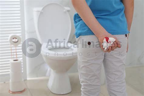 Boy Holding Toilet Paper With Blood Stain In Rest Room Closeup
