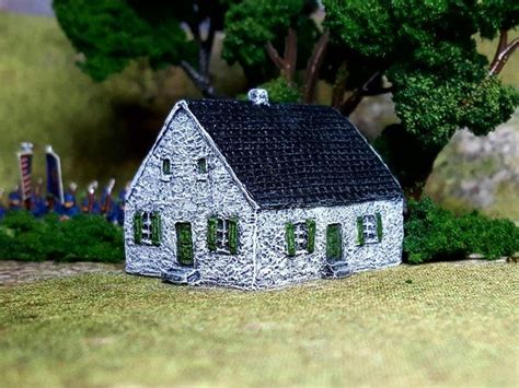 A Small Model House Sitting On Top Of A Green Grass Covered Field Next