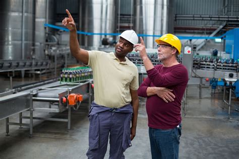 Two Factory Workers Pointing Upwards While Discussing Together Photo