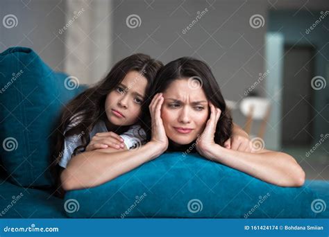 hija adolescente educada apoyando a su joven madre que sufre de dolor de cabeza foto de archivo