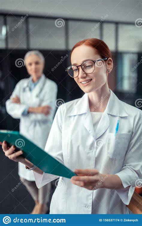 Happy Young Female Doctor Looking At A Clipboard Stock Photo Image Of
