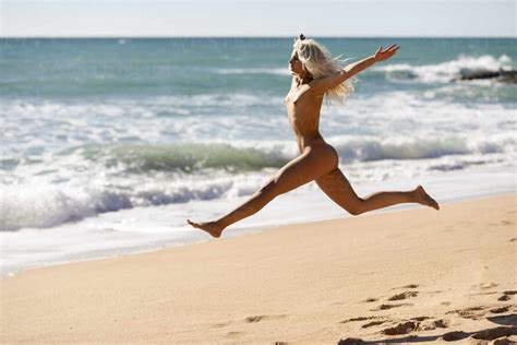 Unbeschwerte Nackte Junge Frau Springt Am Strand Gegen Das Meer