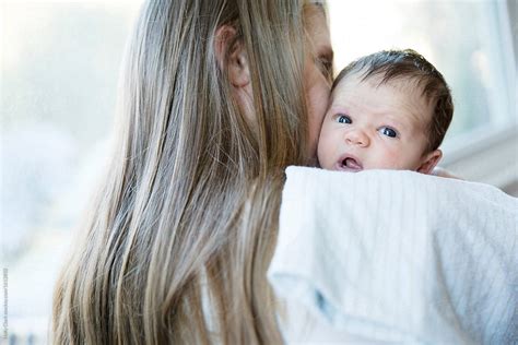 Infant Daughter Looks Over Blond Mother S Shoulder While Being Burped By Stocksy Contributor