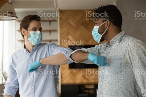 Multiracial Male In Masks Touch Elbows Greeting During Covid19 Stock