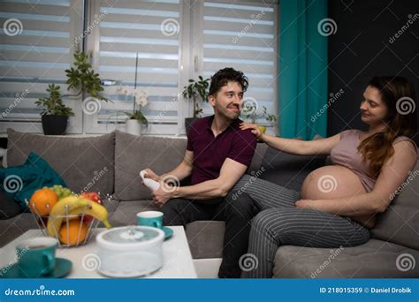 A Husband Massages His Wife S Feet And They Sit Together On The Sofa In The Living Room