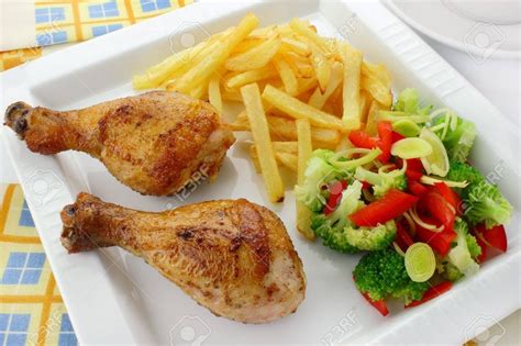 Two chicken legs with french fries and salad on a plate