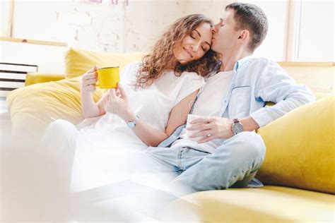 Junge Glückliche Paare Sitzen Und Kuscheln Auf Einem Gelben Sofa In Der Wohnung Liebe Und