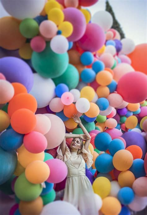 A Woman In A White Dress Surrounded By Balloons
