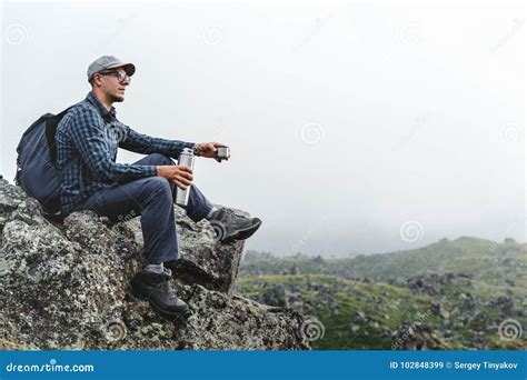 Young Traveler Man Sitting On Top And Holding Thermos In His Hand
