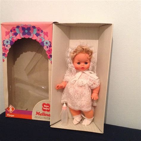 A Small Doll In A Box On A Table Next To A White Wall And Blue Floor