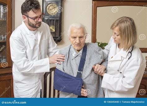 De Arts En De Verpleegster Helpen De Oude Vrouw Van De Stoel Opstaan