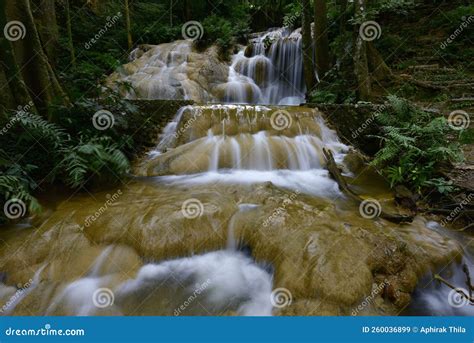 A Beautiful Waterfall In The Green Forest With Green Water Flowing On