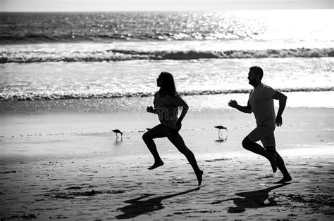 Couple Running On Beach Silhouette Of Young Man And Woman Running Jogging Along The Sea Stock