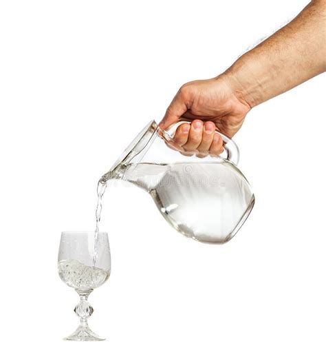 Hand Holding Water Jug And Pouring Water Into Glass Cup Stock Photo