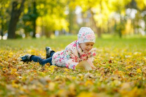 Cute Little Girl Is Reading A Book While Laying On Yellow Autumn Leaves