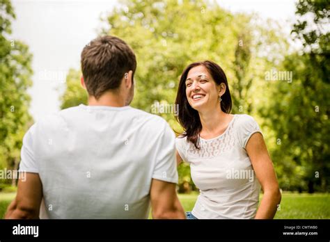 Young Happy Couple Talking Together Outdoor Sitting On Grass Stock