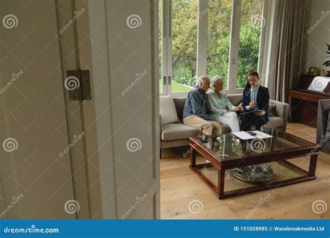 Active Senior Couple Discussing With Real Estate Agent Over Documents In Living Room Stock Image