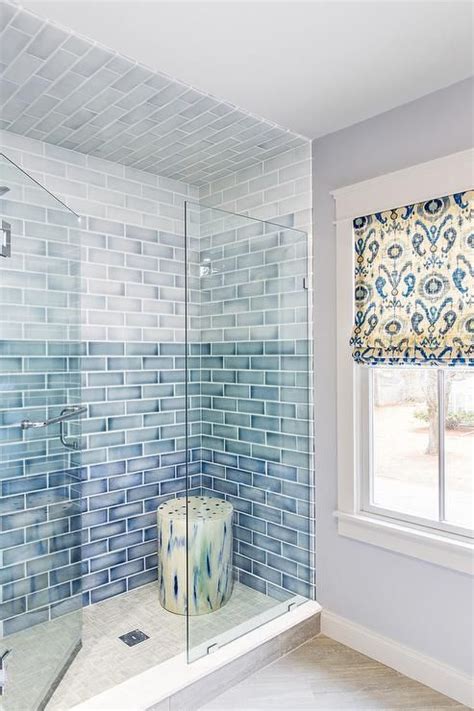 A Seamless Glass Door Opens To A Walk In Shower Clad In Blue Ombre Ceramic Tiles Alongside A