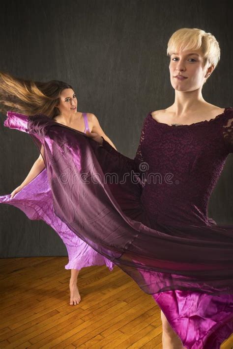 Pair Of Young Women In Dresses Dancing In The Studio Stock Photo