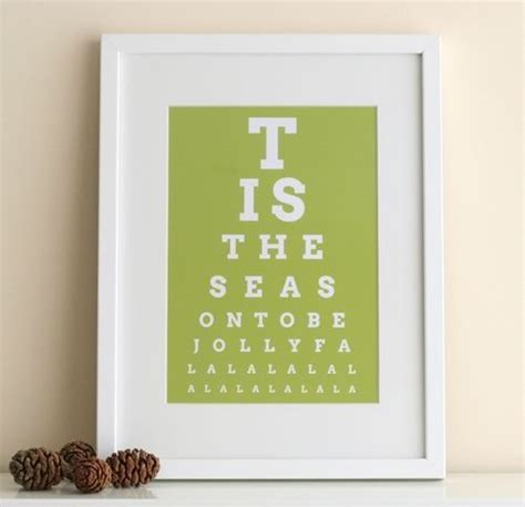 An Eye Chart Print With Pine Cones On The Shelf Next To It And A White Frame