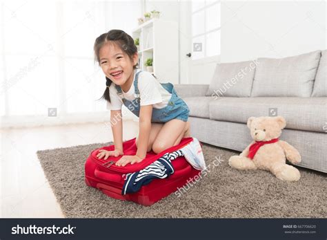 Happy Beautiful Little Kid Girl Kneeling On Suitcase Face To Camera And