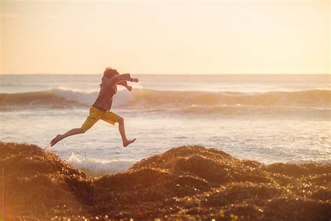 Boy Leaping At Beach At Sunset Del Colaborador De Stocksy Angela