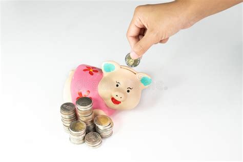 Hand Putting Coin Into Pink Piggy Bank With Coins Pile Stock Photo