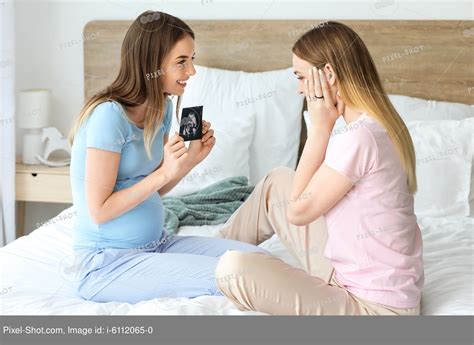 Pregnant Lesbian Couple With Sonogram Image In Bedroom Stock