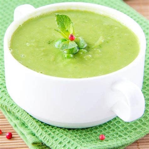 A white bowl filled with broccoli soup on top of a green napkin