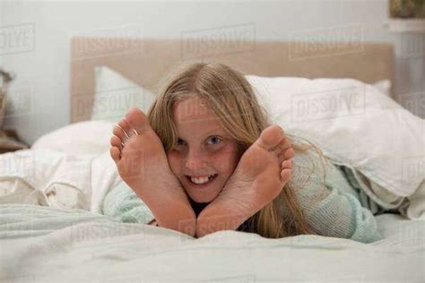 Portrait Of Girl Lying On Bed In Between Feet Stock Photo Dissolve