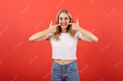 Premium Photo Ð¡heerful Young Girl With Braces Pointing Fingers At Her Mouth Over Red Background