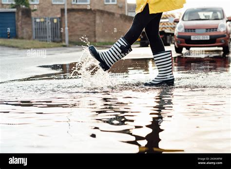 Mujer Divirtiéndose En La Calle Después De La Lluvia Acércate A Las Piernas Femeninas Con Botas