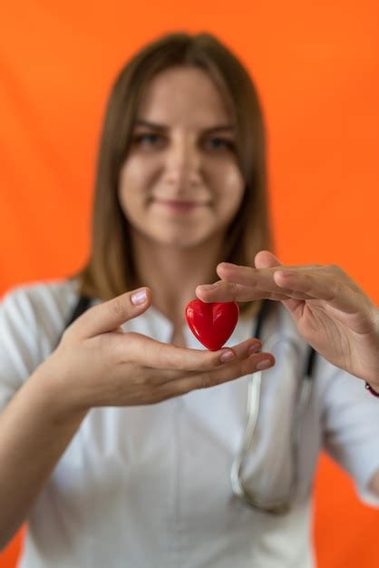 premium photo female doctor or nurse in blue uniform with mask gloves holding small red heart