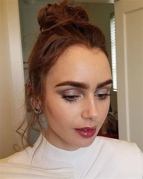 A Close Up Of A Woman With Makeup On Her Face And Hair In A Bun