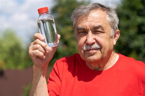 premium photo pportrait of 70 year old elderly man with a bottle of water in the garden