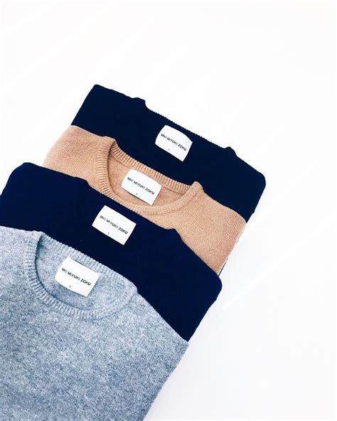 Three Different Colored Sweaters Sitting Next To Each Other On A White