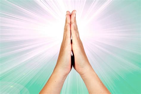 Hands Clasped In Prayer With Rays Of Light On Green Background