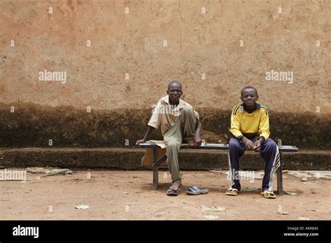 Two Burkinabe Boys Sitting On A Bench Outside Their Home In A Suburb Of